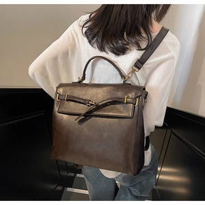 Detail of vintage brown leather backpack worn by model on stairs, showing size and texture