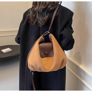 Detail of camel suede tote bag showing soft texture and contrast flap with large buckle