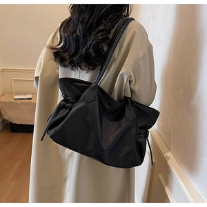 Vue détaillée du sac cabas noir en nylon avec poignées en cuir dans un cadre de vie moderne