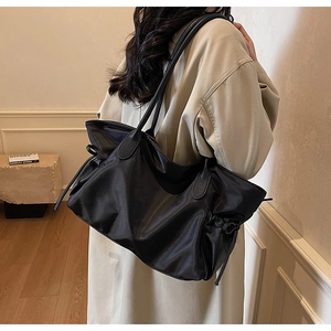 Vue latérale du grand sac cabas en nylon noir imperméable avec nœuds à cordon coulissant