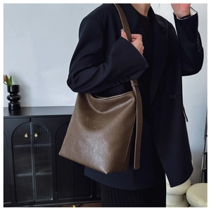Détail d'un sac porté épaule marron foncé avec texture vintage et logo embossé