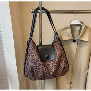 Detail of leopard print tote bag featuring black leather flap and round magnetic buckle