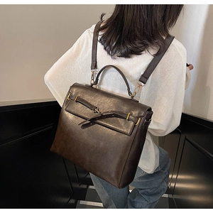 Macro detail of vintage dark brown faux leather backpack with gold buckle and handle