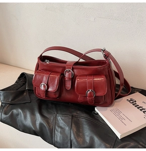 Detailansicht einer dunkelroten, glänzenden PU-Leder-Schultertasche mit Silberschnallen
