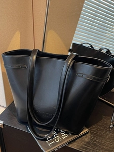 Minimalist black large capacity leather tote bag with shoulder straps and logo detail