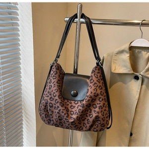 Close-up of leopard print tote bag with black leather flap and round buckle detail