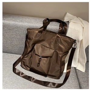 Close-up of brown nylon tote bag with decorative chain and front flap pocket detail