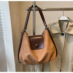 Detail of caramel brown tote bag with dual straps and silver metal buckles on display