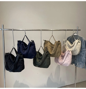 Detailed row of quilted nylon tote bags in six colors hanging on a metal rack