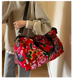 Detail of large travel bag with traditional red floral pattern and adjustable strap