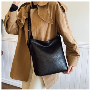 Détail du sac seau noir plissé en cuir avec logo embossé sur la bandoulière