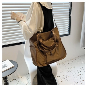 Detail of dark brown waterproof nylon tote bag with functional front pocket and shoulder strap