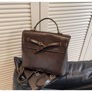 Detail view of a vintage dark brown leather backpack with golden metal buckle hardware