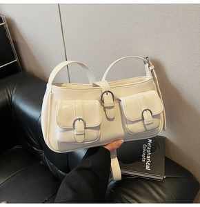 Detailansicht der cremeweißen Umhängetasche mit zwei Vordertaschen und silbernen Schnallen