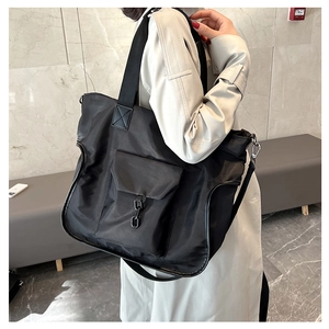 Close-up of black nylon tote bag with industrial metal buckle and wide shoulder strap