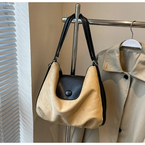 Detail of the khaki suede tote bag featuring black leather contrast straps and round buckle