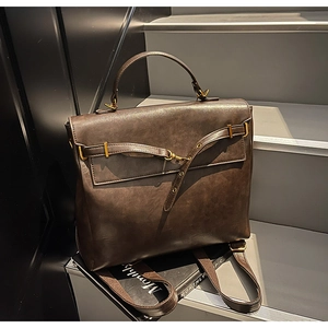 Detailed view of dark brown leather backpack with gold buckles on a vintage book