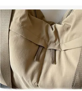 Close-up of khaki ripstop nylon fabric texture and stitching on a tote bag