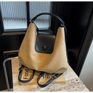 Detail of khaki frosted tote bag with black leather accents and silver magnetic buckle