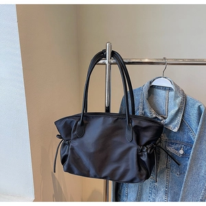 Détail du sac cabas en nylon montrant les coutures en cuir et le cordon latéral