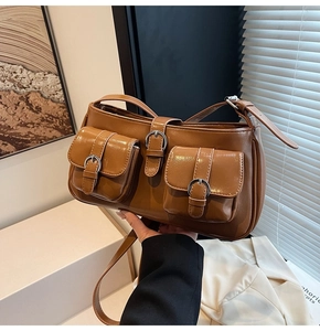 Detail der braunen Kunstledertasche mit doppelten Schnallentaschen und Schultergurt