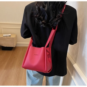 Close-up of fuchsia lychee leather bucket bag with embossed logo on a model