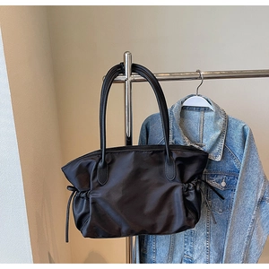 Détail du sac de voyage en nylon noir avec anses en cuir et cordons de serrage réglables