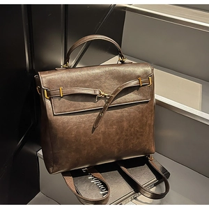 Detail view of dark brown vintage backpack in matte leather on a dark grey staircase