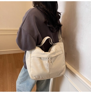 Detail of a large beige nylon tote bag showing its adjustable strap and soft drape