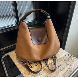 Detail of premium brown suede and leather tote bag featuring round buckle and metal zipper