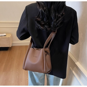Brown lychee leather bucket bag shown as a shoulder bag with fine texture and logo