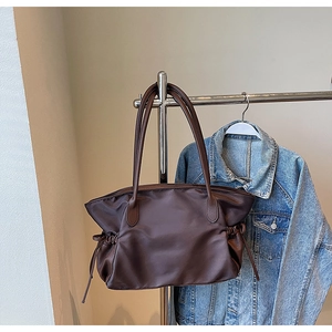 Détail du grand sac de voyage en nylon marron foncé avec poignées en cuir et cordon latéral
