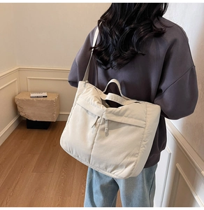 Detail of off-white nylon tote bag with dual zipper pockets and adjustable shoulder strap
