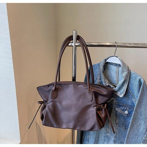 Détail d'un grand sac cabas en nylon marron foncé avec anses en cuir posé sur un cintre