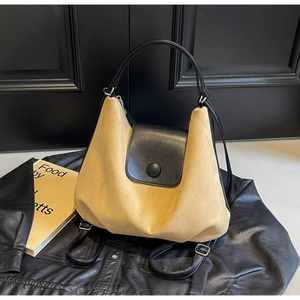 Detail of minimalist beige and black two-tone hobo bag with adjustable straps
