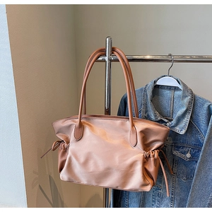 Détail du sac de voyage en nylon rose avec poignées en cuir marron sur cintre