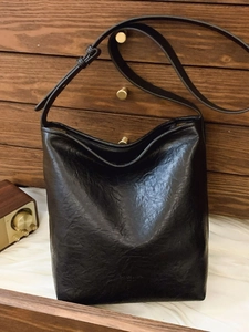 Sac seau plissé noir avec bandoulière réglable sur fond de style vintage
