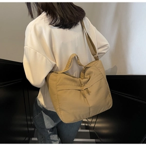 Detail of khaki nylon tote bag showing wide shoulder strap and functional double pockets