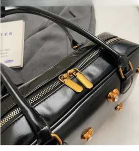 Close-up of dual golden zippers and metallic rivet details on black leather bag