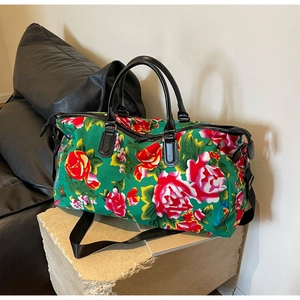 Detailed close-up of a floral travel bag with large red peonies on a green background