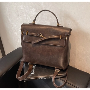 Detail of vintage dark brown leather backpack with gold clasp and matte texture on a magazine