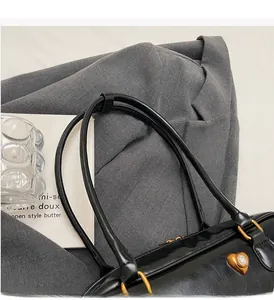 Detail of black leather shoulder bag handle with golden heart charm and metal ring