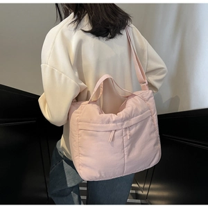 Detail of pink quilted nylon tote bag with plush padded texture and adjustable shoulder strap