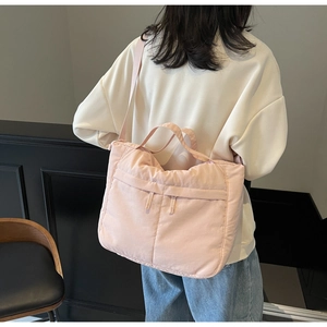 Detail view of pink quilted nylon tote bag showing soft texture and shoulder strap