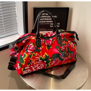 Detail of red travel bag with ethnic peony pattern and durable leather handles