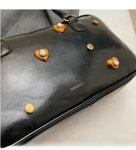 Detail of black leather shoulder bag with gold heart studs and sparkling crystals
