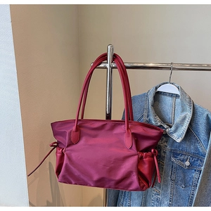Détail du cabas en nylon bordeaux avec poche latérale à cordon et poignée en cuir
