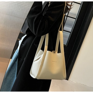 Close-up of cream pebble leather bucket bag showing grain texture and embossed logo