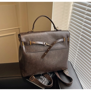 Detail of vintage dark brown PU leather backpack with gold buckle and top handle