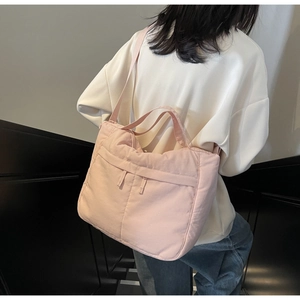 Detail view of large pale pink nylon tote bag with puffer texture on female model